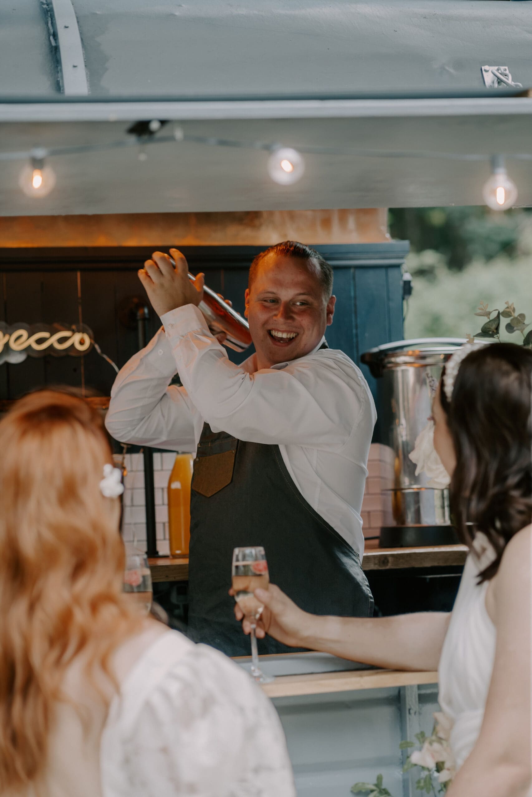 The Bubble Box staff shaking a cocktail at a wedding in the mobile horsebox bar.